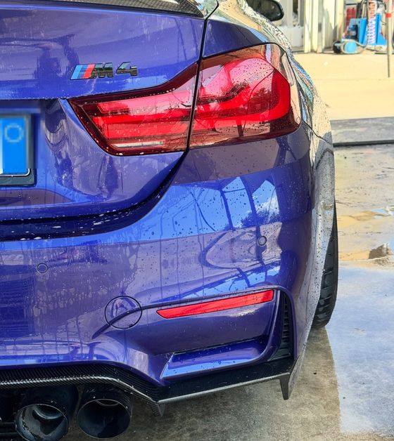 Il posteriore di una BMW M4 blu appena lavata, con i riflessi puliti
