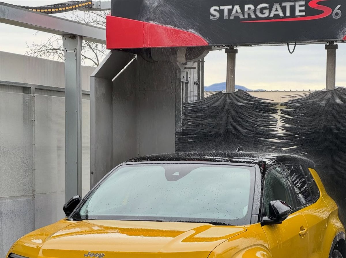 Un’auto sotto il portale di lavaggio Aquarama Stargate S6, con le montagne della valle sullo sfondo
